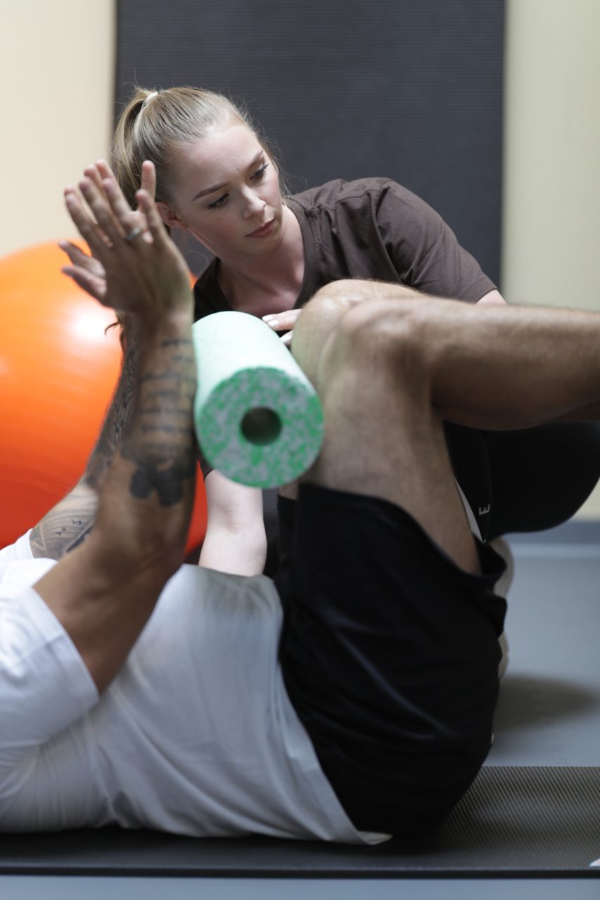 Physiotherapeutisch begleitete Übung mit Faszienrolle beim Wiedereinstieg nach Sportverletzung.